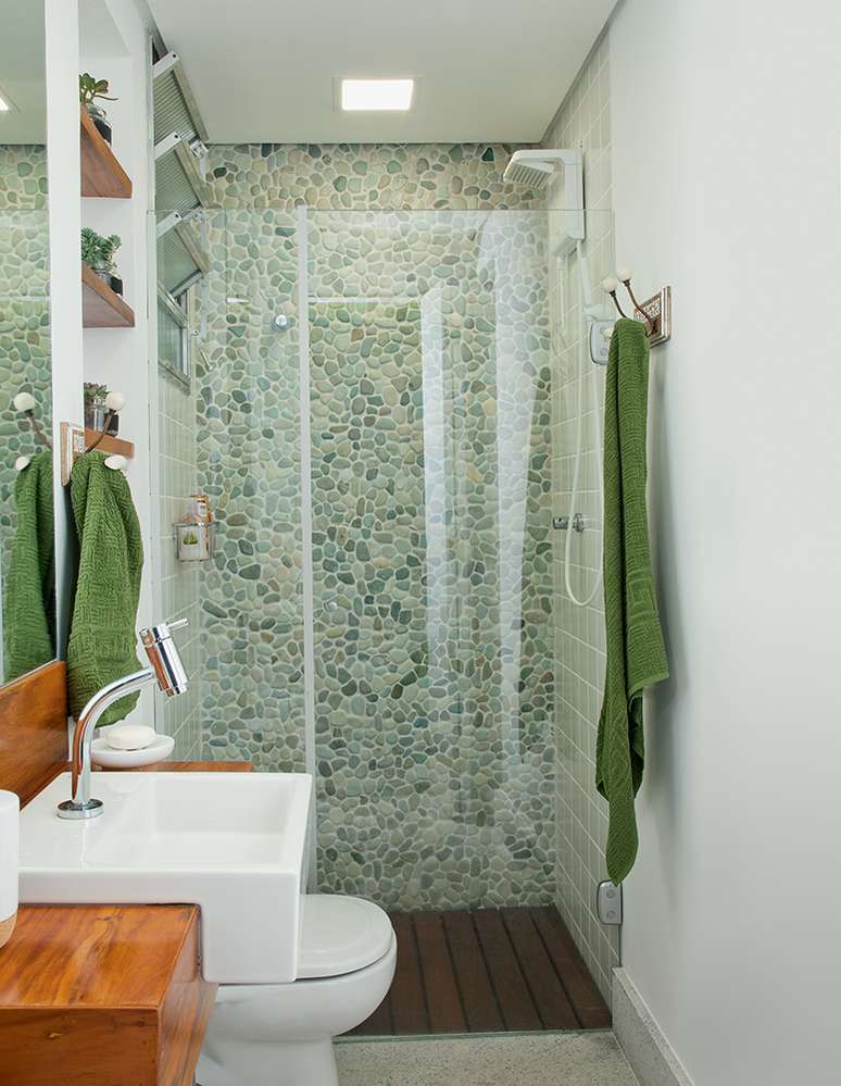 Para compor com os seixos, sem concorrer com eles, as demais paredes receberam azulejos cer&acirc;micos lisos em um tom rebaixado de verde. Projeto Naka Rosa Design.