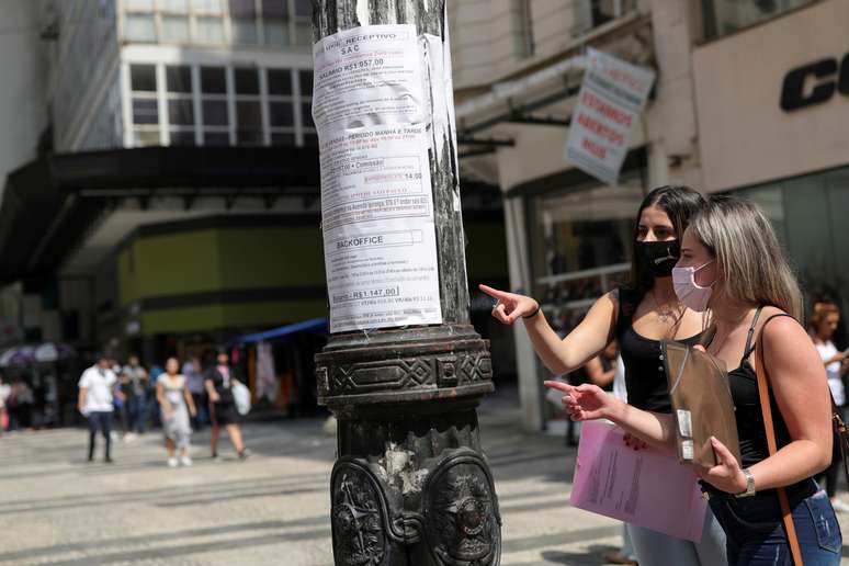 Mulheres olham anúncios de emprego afixados em poste de luz no centro de São Paulo 