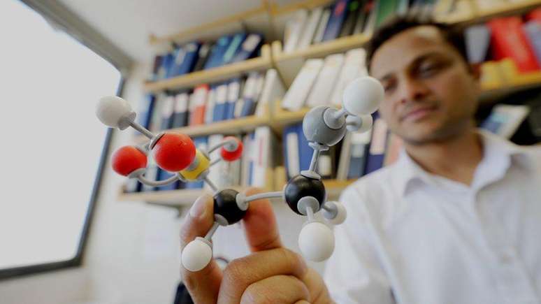 Vijay Yadav segurando um modelo da estrutura química da taurina