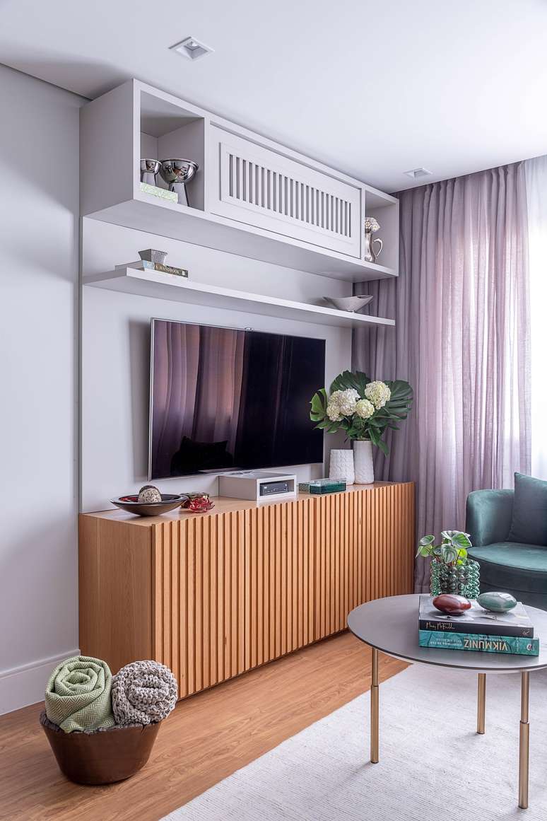 In this living room designed by architect Carina Dal Fabbro, the TV stand also acts as a buffet for storing the residents' belongings.  Above, the niche with slatted furniture camouflages the air conditioning, as well as contributing to the furnishings.