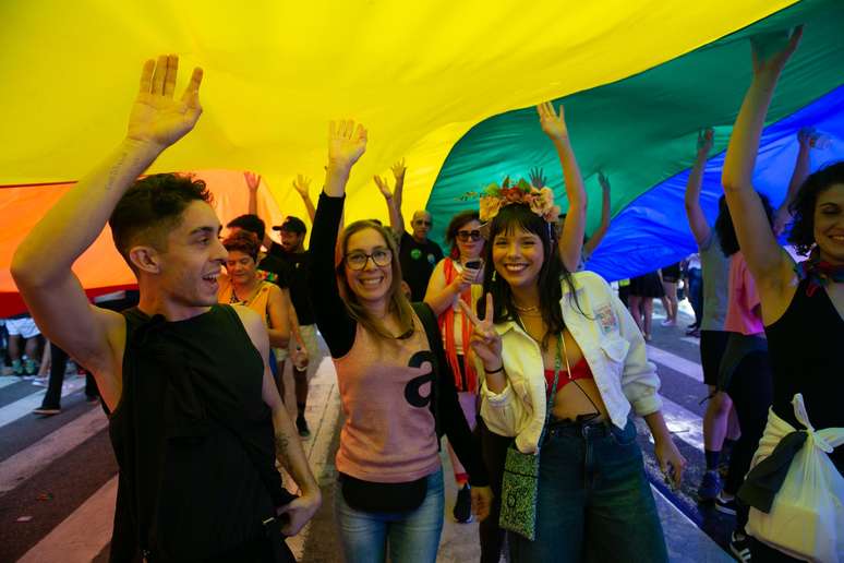 Público passa por baixo de bandeirão na 27ª Parada do Orgulho LGBT+