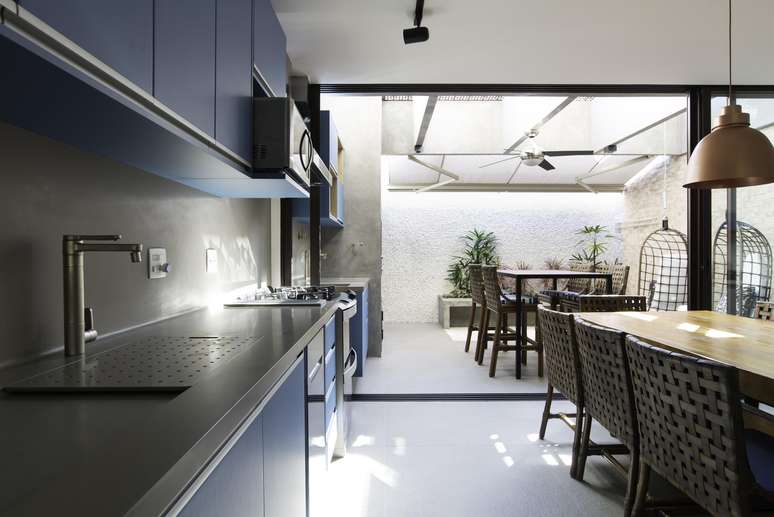 In this pantry-kitchen integrated with the external area of ​​the residence, the project created by Patricia Miranda formed a single panel up to the barbecue.  In the specifications, Corian, which accompanies the same shade of burnt concrete on the walls, provided an interesting counterpoint to the blue of the carpentry.