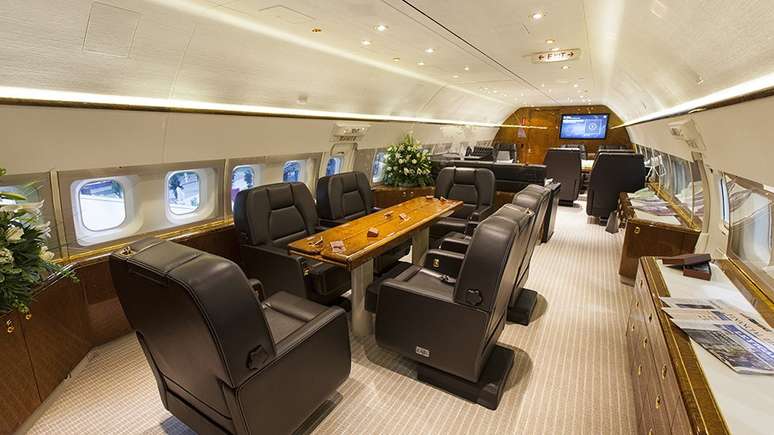 Sala de reunião com mesas e poltronas confortáveis em avião de luxo