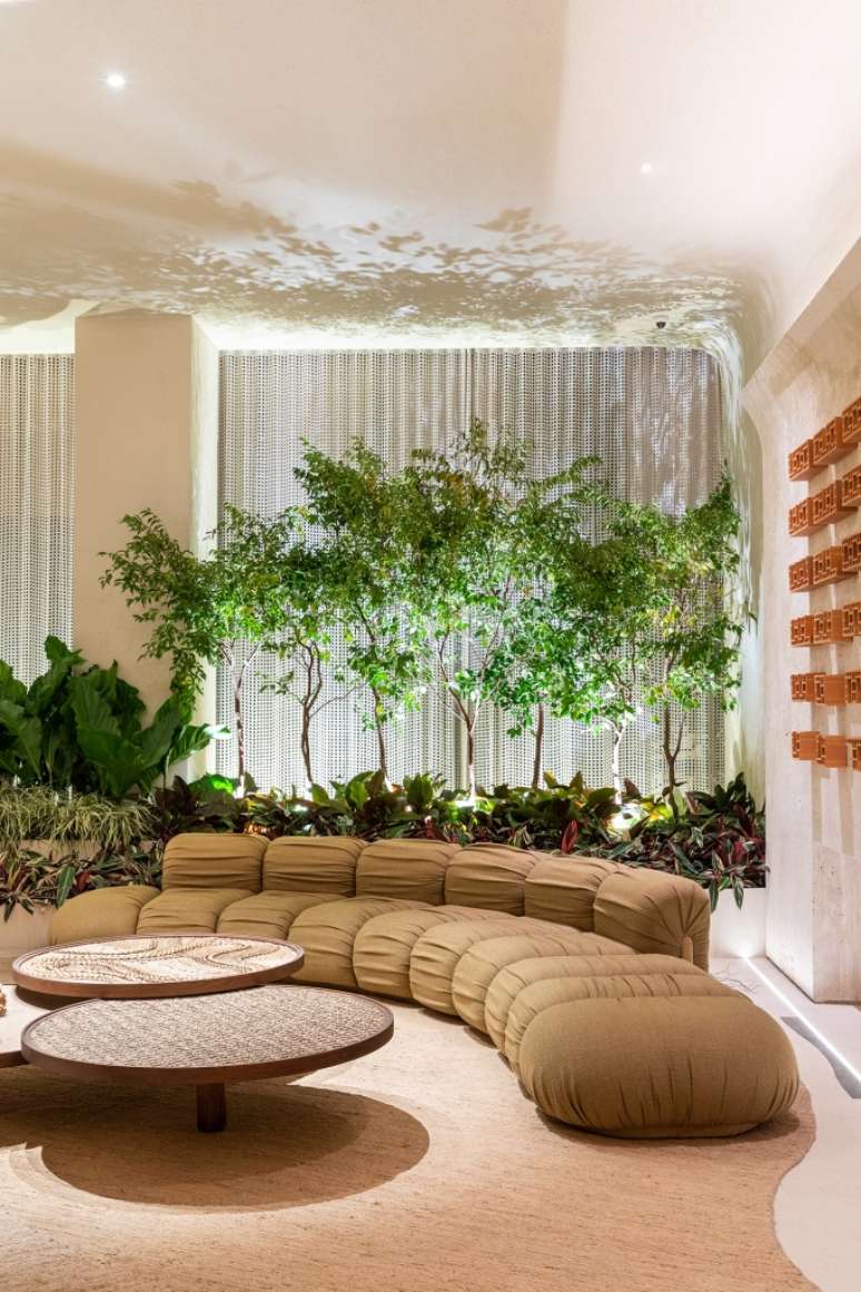 Signs of time and stories mark the furnishings of this loft.  Project by SUITE Arquitetos for CASACOR SP 2023. In the photo, living room with curved sofa and garden.