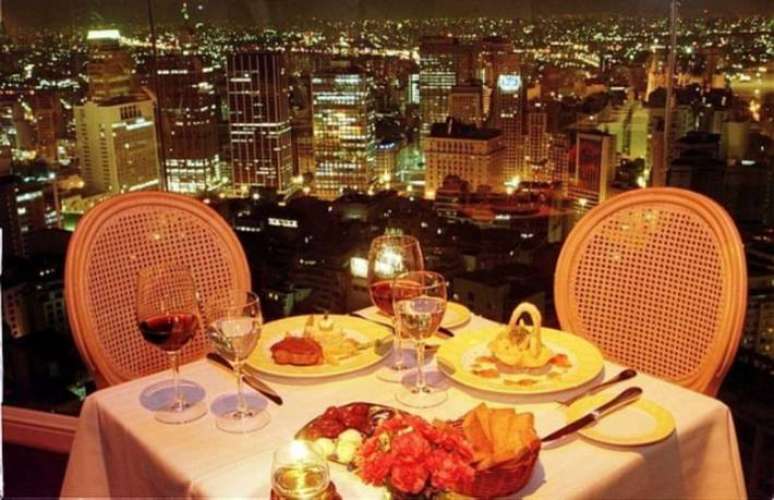 Mesa de jantar do restaurante Terraço Itália, no Edifício Itália, com vista noturna da região central da capital paulista.