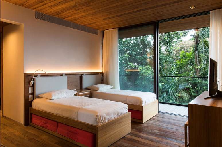 Casa de 153 m&sup2; se camufla em meio &agrave; natureza do litoral paulista. Projeto de Daniel Fromer, interiores de Julyana Bortolotto. Na foto, quarto com vista para a mata e forro de madeira.