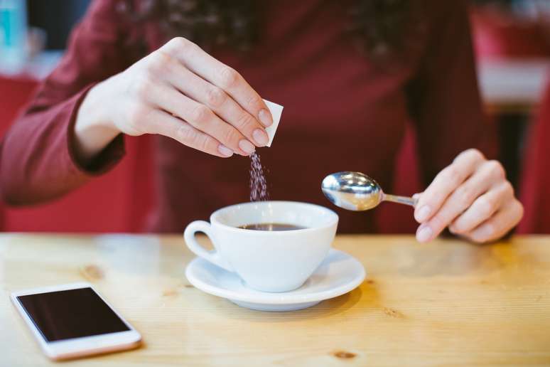 Mulher usa adoçante no café; aspartame foi classificado como potencialmente cancerígeno