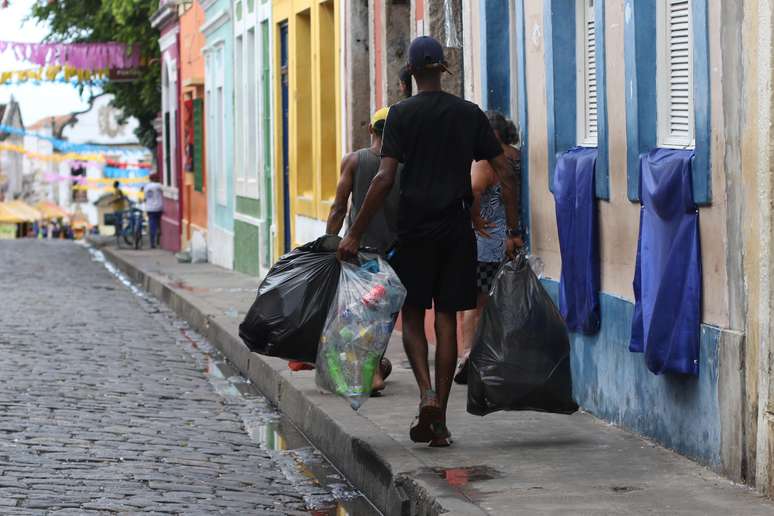 Homem carrega saco com latinhas de alumínio em Olinda