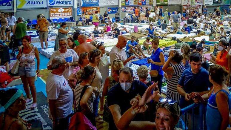 Turistas abrigados em um estádio em decorrência de incêndios florestais