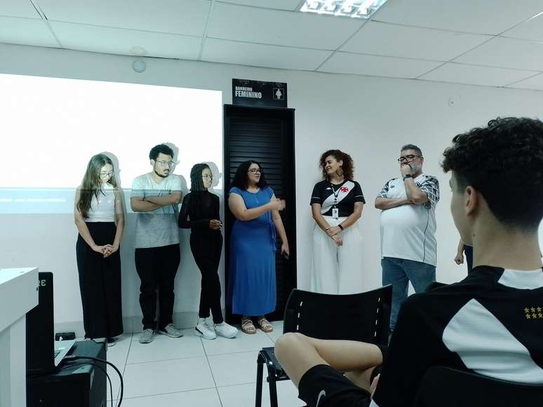 Com a camisa do Vasco, Thaís, coordenadora da oficina, apresenta o documentário ao lado de seus alunos 