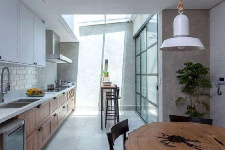 In the kitchen integrated with the service and dining area, a high table with stools and a hob was installed next to the stove. 