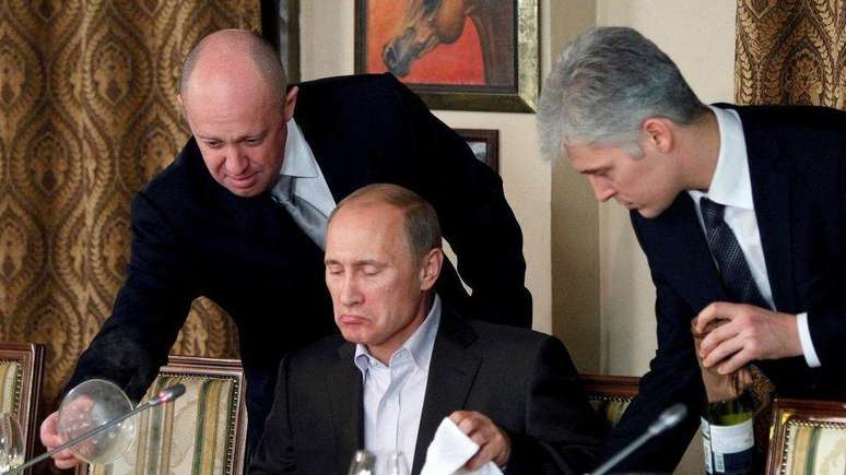 Yevgeny Prigozhin (&agrave; esq.) servindo Vladimir Putin (centro) em um jantar em 2011