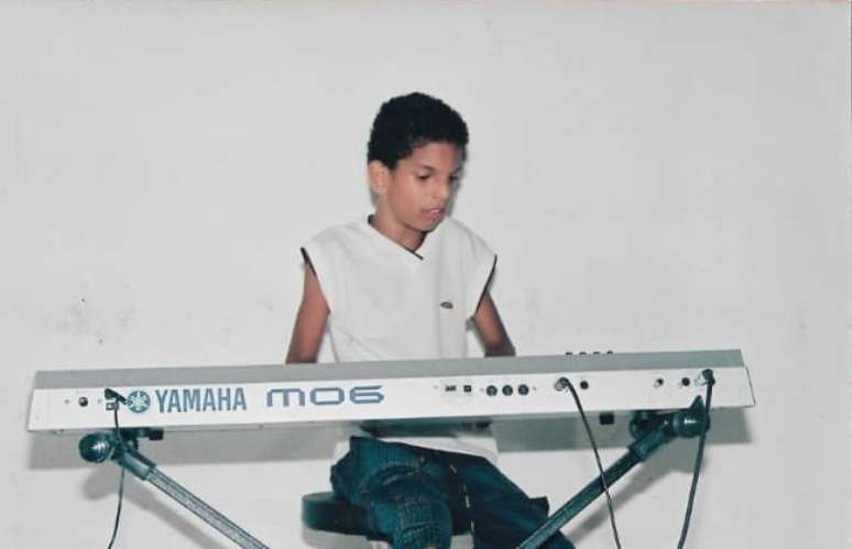 Alvaro tocando piano na infância, quando aprendeu a tocar o instrumento com o pai