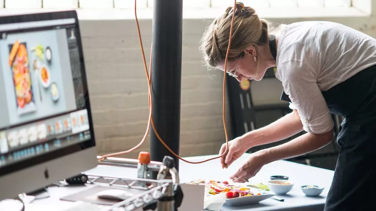 Imagem mostra mulher montando prato para fazer uma foto publicitária