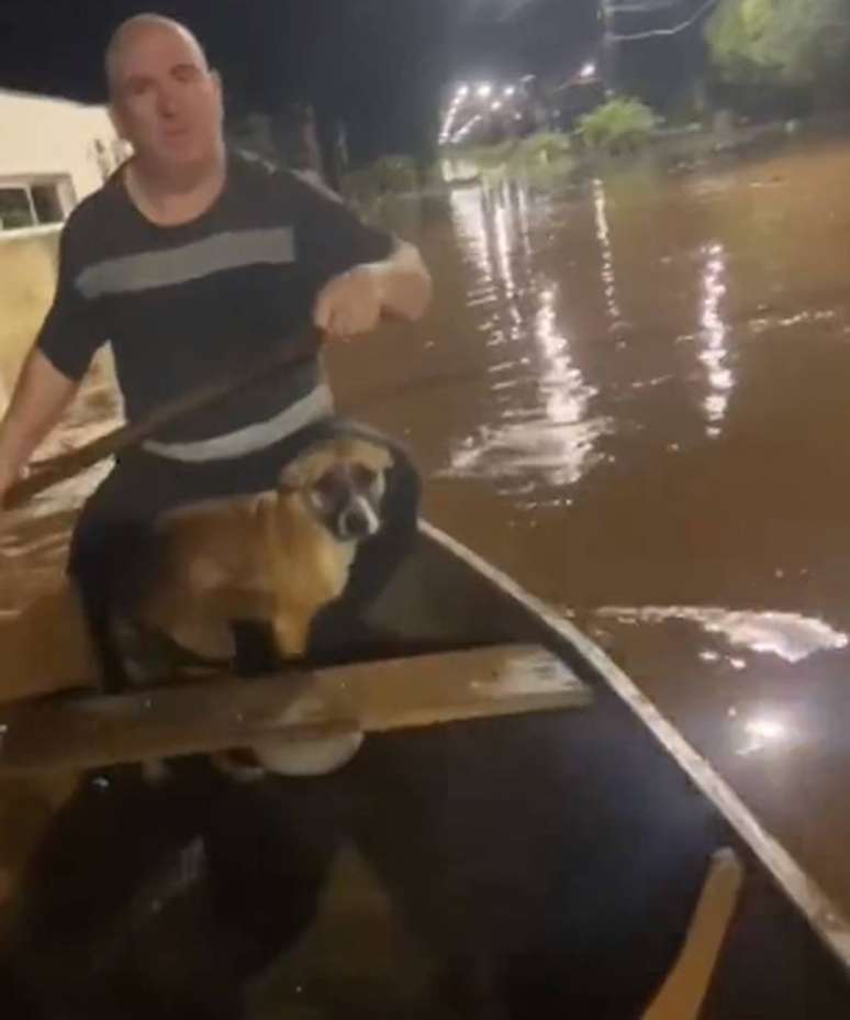 Pai e filha percorrendo ruas de Muçum, dentro de um bote, salvam cachorro.