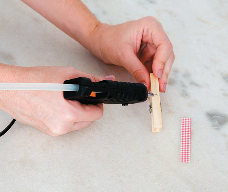 Manually applying hot glue to a fastener to make a tuna can lamp