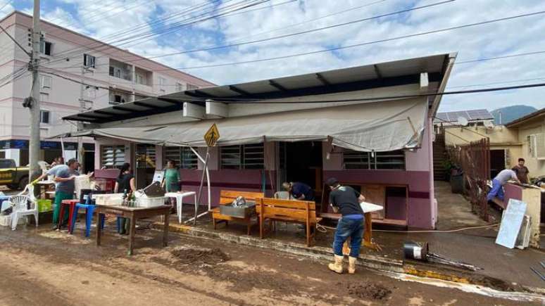 Moradores de Roca Sales limpam móveis após suas casas serem atingidas pelas enchentes após passagem de ciclone no Rio Grande do Sul.