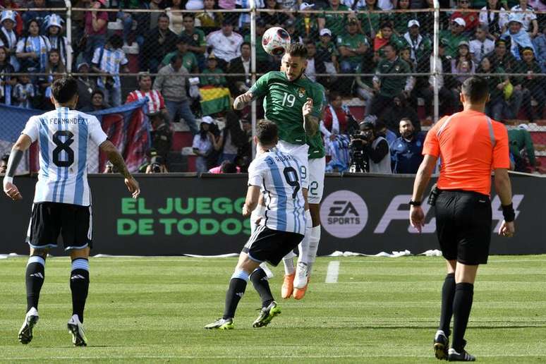 Ursino (de vermelho) rechaça a bola e é observado por Julian Álvarez (camisa 9)