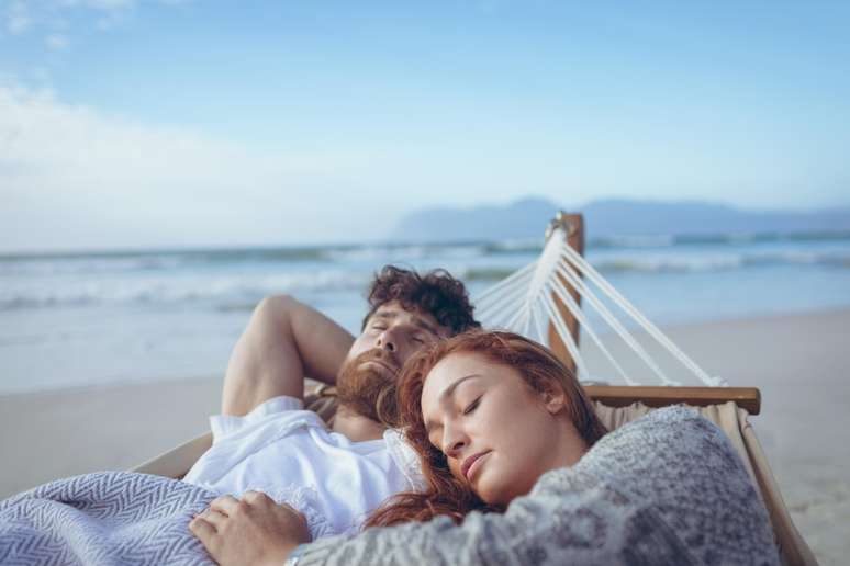 Casal dormindo na rede na praia