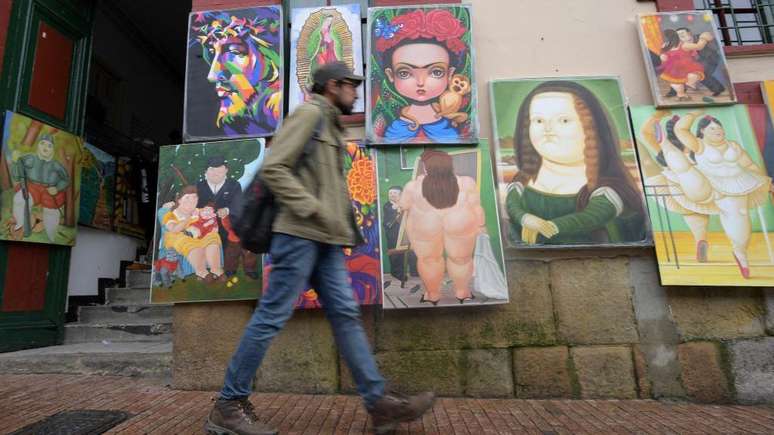 Homem caminha ao lado de réplicas de desenhos de Botero no aniversário de 90 anos do artista em Bogotá, em 2022