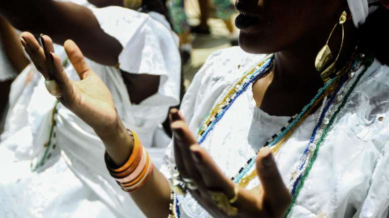 Imagem mostra mulher negra em reza de candomblé.