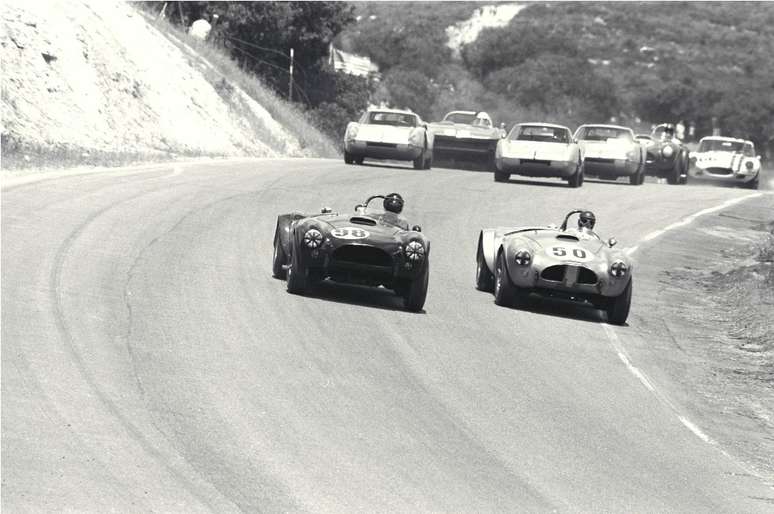 Ed Leslie (#98) e Ken Miles (#50) com carros da Corvette ao fundo,Laguna Seca, 1963
