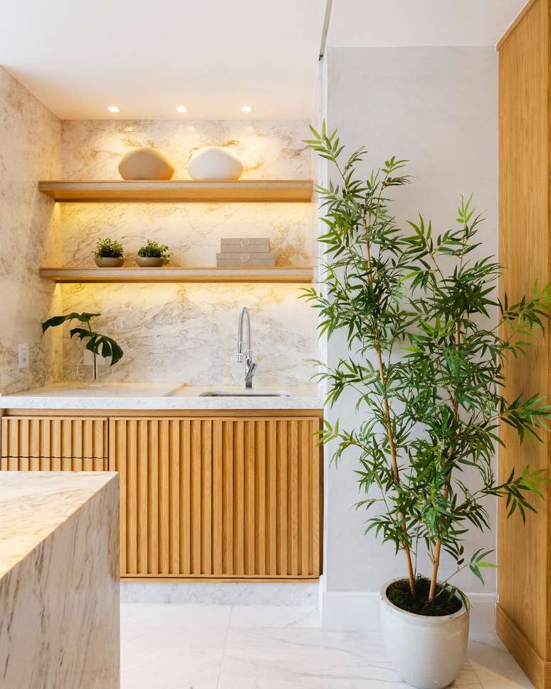 In the kitchen area, both the sink top, the wall cladding and the island were covered in Matarazzo marble.  The softness of its white base was accentuated by the slatted effect, in a light tone, of the fixtures present in the project conceived by architects Renata Iervolino and Eduardo Tambellini.