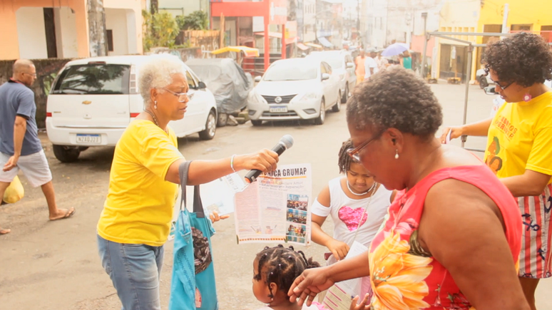 Frame da reportagem "Contos verdade com Tialila" mostra a ativista Rita Santa Rita distribuindo jornal do Grupo de Mulheres do Alto das Pombas (GRUMAP), em Salvador (Foto: Reprodução)