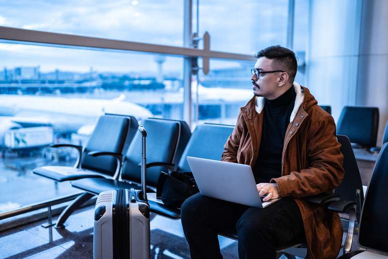 Jovem trabalhando remotamente no aeroporto 