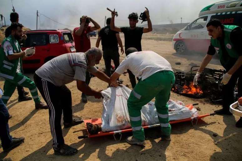 Paramédicos transportam os corpos de dois jovens palestinos cuja motocicleta foi atacada perto da fronteira entre a Faixa de Gaza e Israel