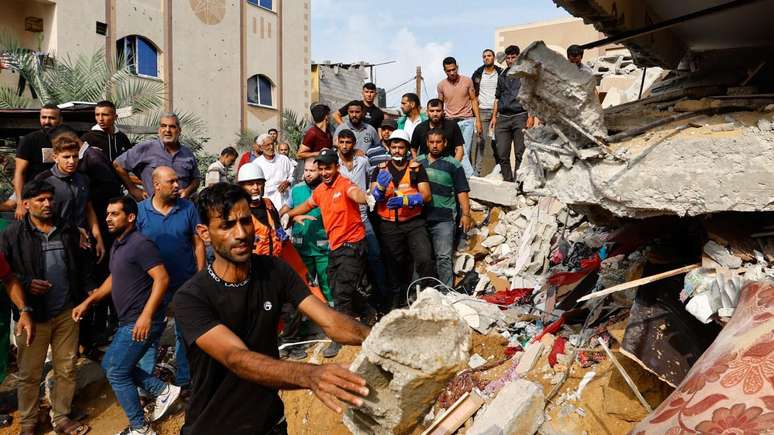 Palestinos observam uma casa destruída em ataques israelenses em Khan Younis, no sul da Faixa de Gaza