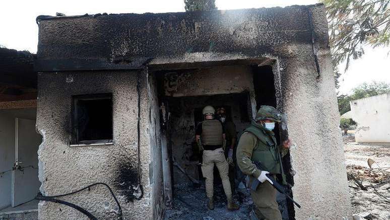 Soldados inspecionando casa parcialmente destruída em Kfar Aza