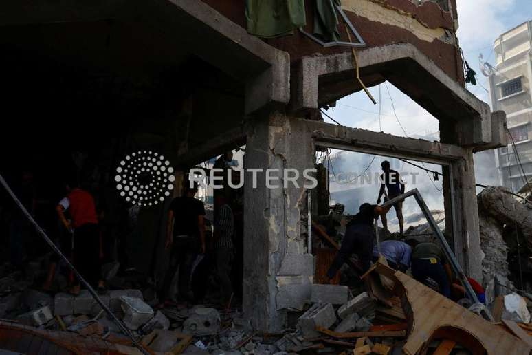Palestinos caminham em escombros ap&oacute;s ataques israelenses em Khan Younis, no sul da Faixa de Gaza
10/10/2023 REUTERS/Ibraheem Abu Mustafa