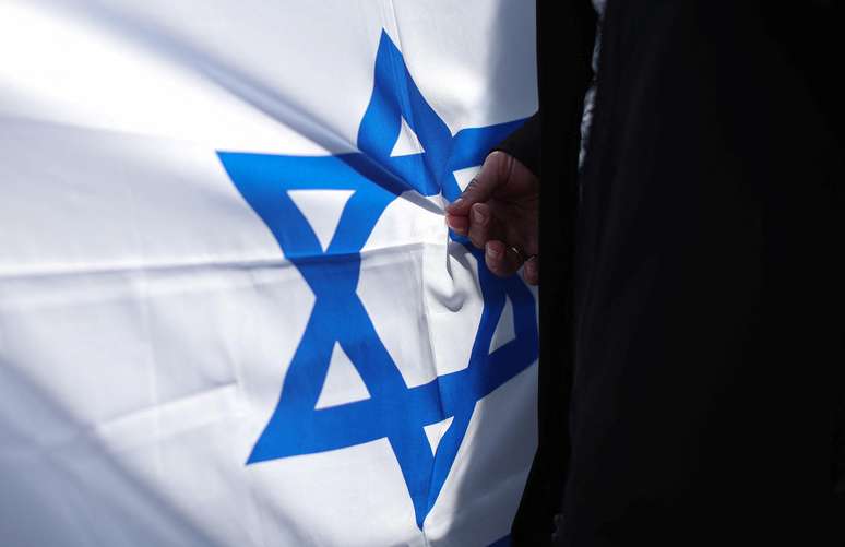 Uma pessoa segura a bandeira de Israel em ato pela paz, ap&oacute;s guerrilheiros do Hamas invadirem territ&oacute;rio israelense