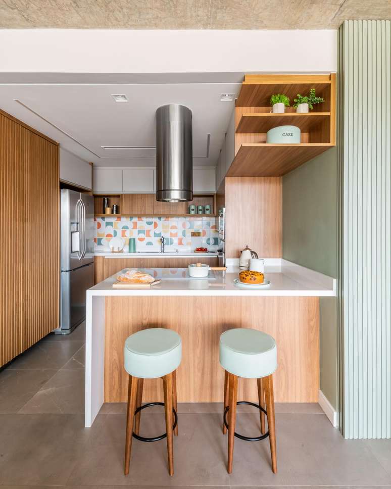 O verde menta combina com qualquer ambiente da casa, tanto como cor predominante, como em um papel secundário. Neste duplex realizado pelo arquiteto Bruno Moraes, ele resultou na sensação de tranquilidade e, ao se reunir com a madeira do mobiliário e o revestimento colorido do backsplash, tornou-se original e aconchegante | Projeto BMA Studio.