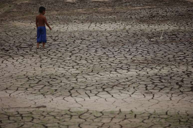 Em Manaus, um menino caminha pelas redondezas do Rio Negro, que atingiu sua maior seca em 121 anos