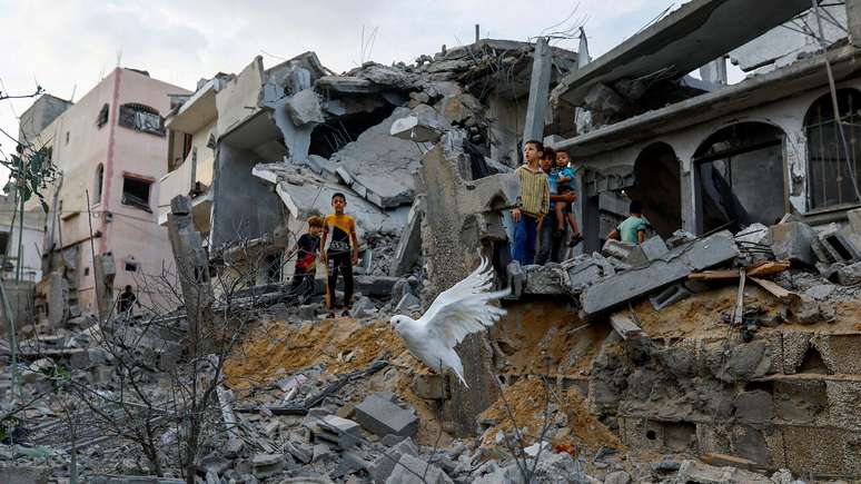 Uma pomba voa sobre os escombros de casas em Khan Younis, no sul da Faixa de Gaza