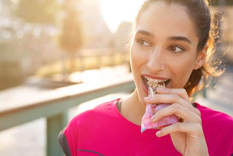 Imagem meramente ilustrativa de uma mulher comendo uma barrinha de cereal