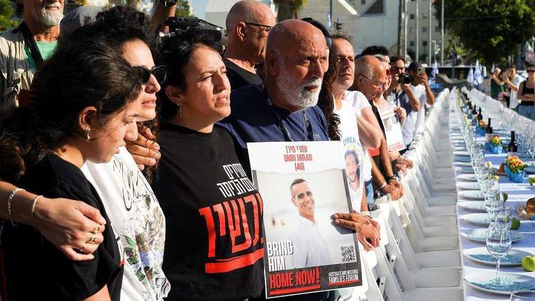 Em manifestação em Tel Aviv, famílias de israelenses mantidos como reféns aparecem ao lado de mesa de jantar posta com cadeiras vazias que representam simbolicamente os sequestrados