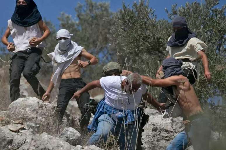 Colonos israelenses mascarados atacando fazendeiros palestinos na Cisjordânia em outubro de 2020