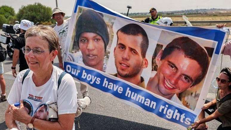 Ativistas israelenses pedem libertação de Avera Mengistu (à esquerda) e a devolução dos corpos dos soldados Oron Shaul (centro) e Hadar Goldin (à direita)