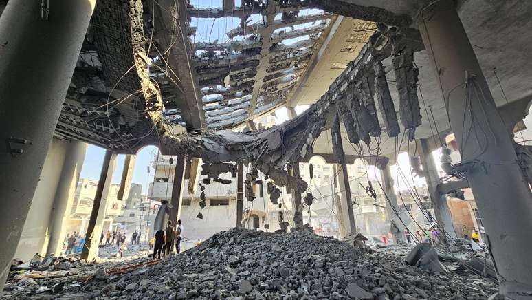 Palestinos inspecionam escombros de uma mesquita destruída em ataques israelenses, no norte da Faixa de Gaza