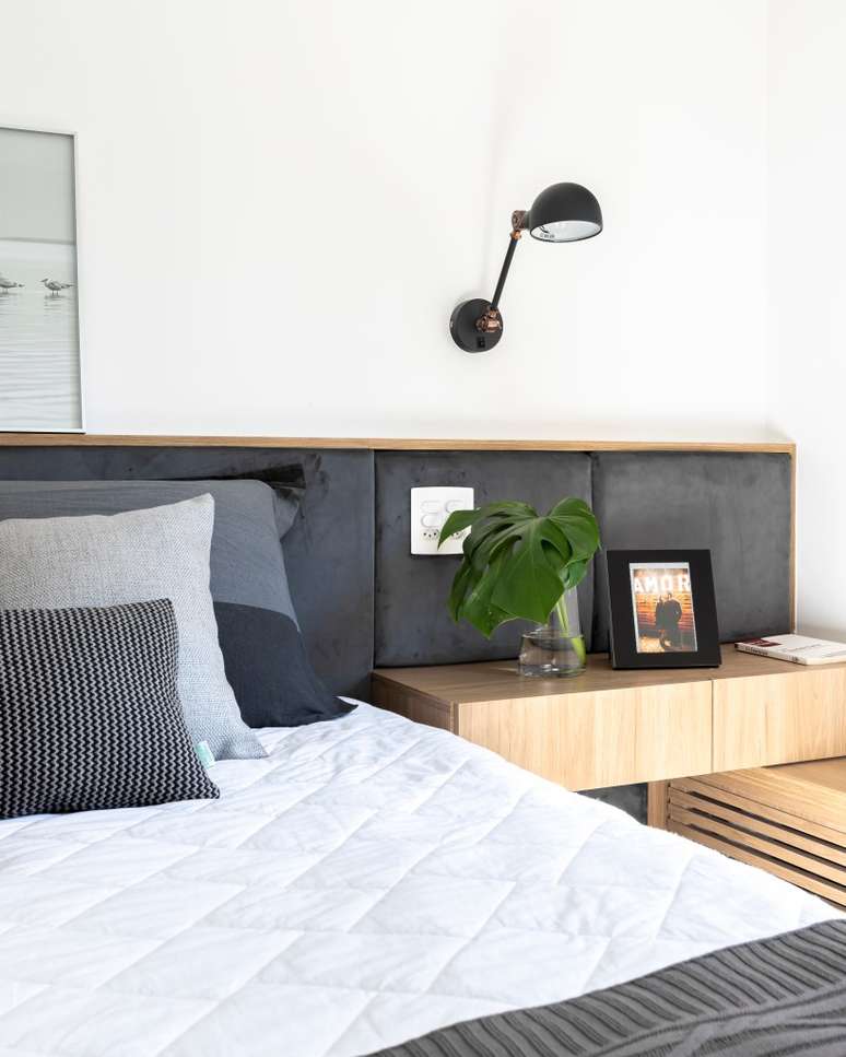 Com or&ccedil;amento baixo, ap&ecirc; de 70m&sup2; ganha m&oacute;veis planejados e churrasqueira. Projeto de Studio Monfr&eacute;. Na foto, quarto com cabeceira acolchoada e mesa lateral de madeira.