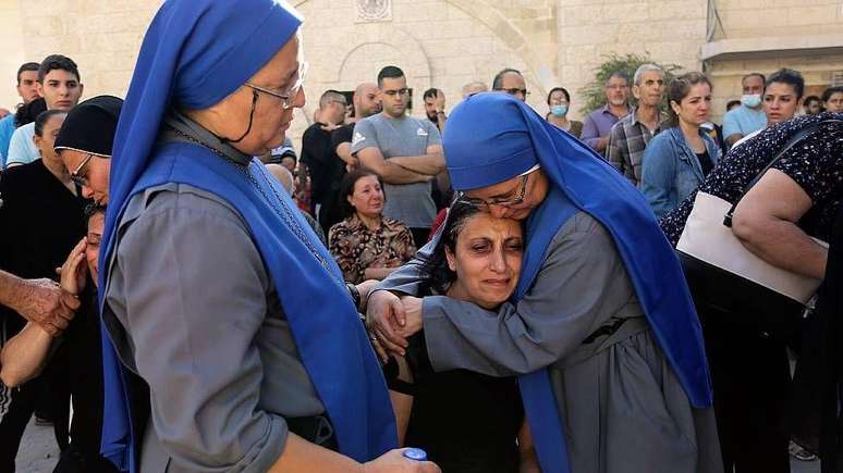 María del Perpetuo Socorro (à esquerda) e María del Pilar Llerena Vargas, gêmeas, consolam parentes das vítimas do bombardeio israelense que atingiu o complexo da Igreja Ortodoxa de Santo Porfírio em 19 de outubro