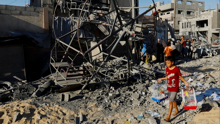 Criança caminha em área que foi alvo ataques israelenses a edifícios em Khan Younis, no sul da Faixa de Gaza