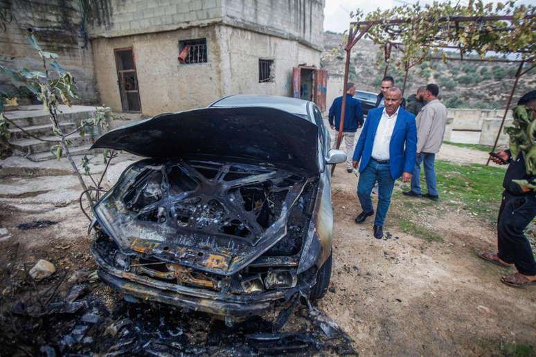Palestinos assistem a um de seus veículos supostamente incendiado por colonos israelenses na Cisjordânia