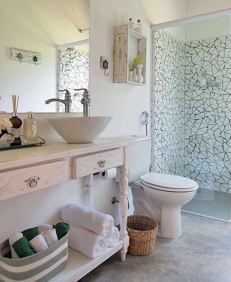Um estilo de decoração mais afetiva se revela neste banheiro de uma casa de campo em Ibiúna, SP. Assinado pela arquiteta Beatriz Castanho, o projeto exibe elementos rústicos, como o aparador e a prateleira com pintura desgastada, o piso de cimento queimado e os caquinhos de azulejo (Arhus Alto Brilho Branco, de 32 x 57 cm, da Cecafi).