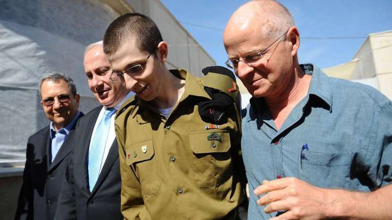 Gilad Sahlit, com seu pai Naom (à direita), e o então ministro da Defesa israelense, Ehud Olmert, e o primeiro-ministro Benjamin Netanyahu, foi libertado pelo Hamas em troca de 1.027 prisioneiros palestinos