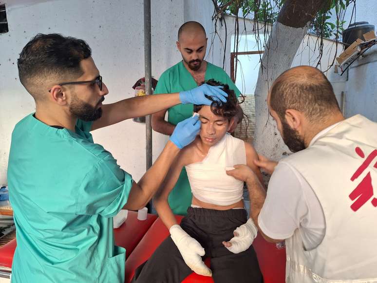 Enfermeiro de Médicos Sem Fronteiras atendem a garoto com queimaduras, em Gaza, vítima de ataque aéreo, em 19 de outubro