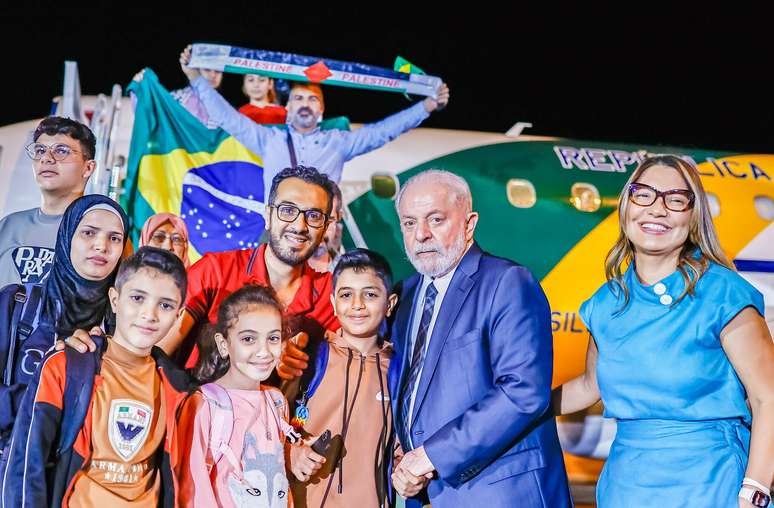 Lula e Janja recebem família vinda de Gaza; ao fundo, o avião da FAB usado no resgate